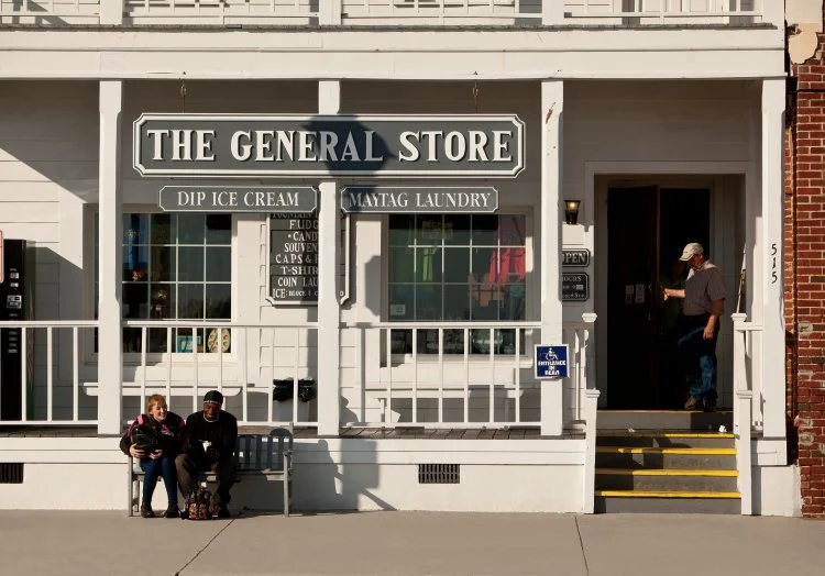 The General Store storefront with porch seating and an open door as people enter