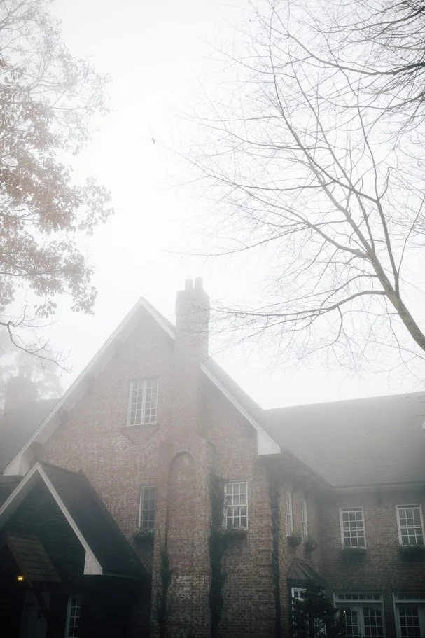 Moody exterior of a brick wedding venue surrounded by fog.