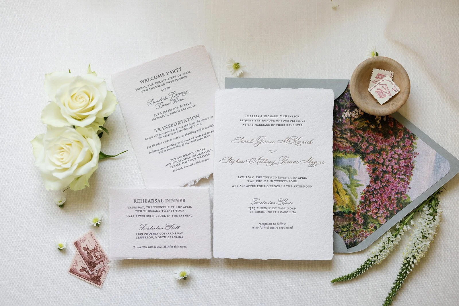 Minimal wedding invitation suite flatlay with white roses and stationery on a light background.