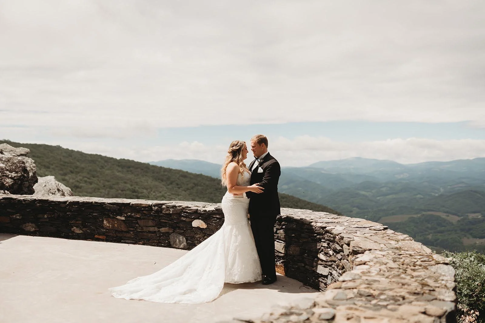 Bride and groom embracing on a stone terrace with panoramic mountain views