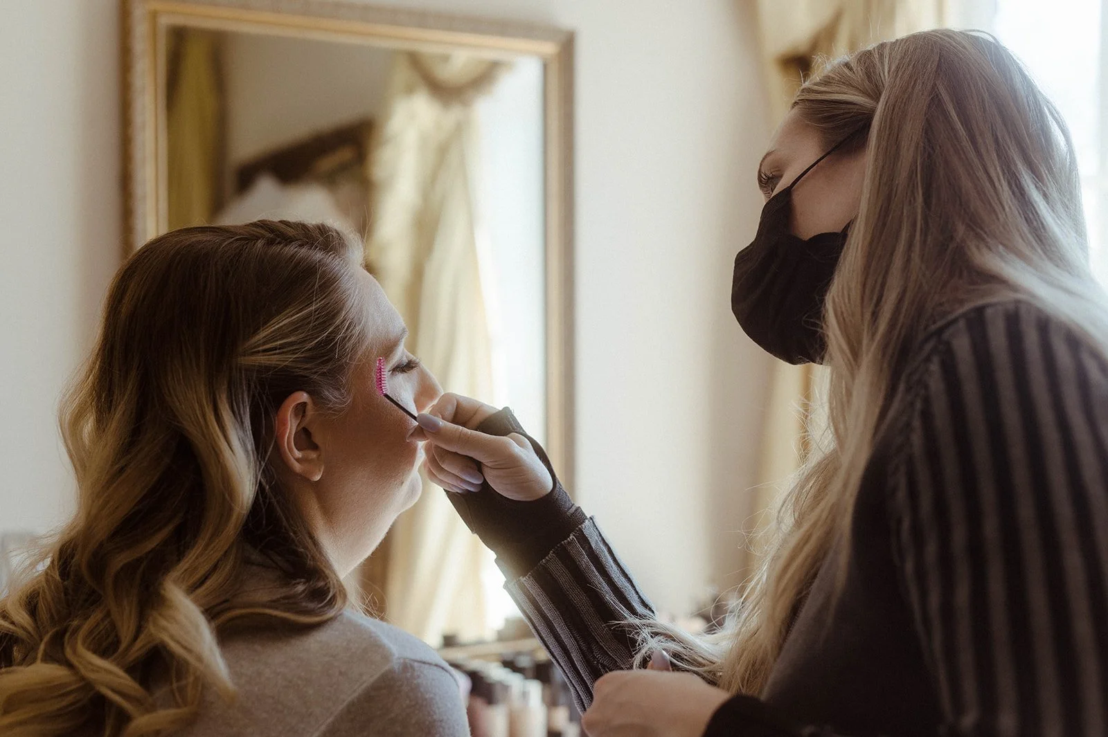 Makeup artist applying eye makeup to the bride during getting ready