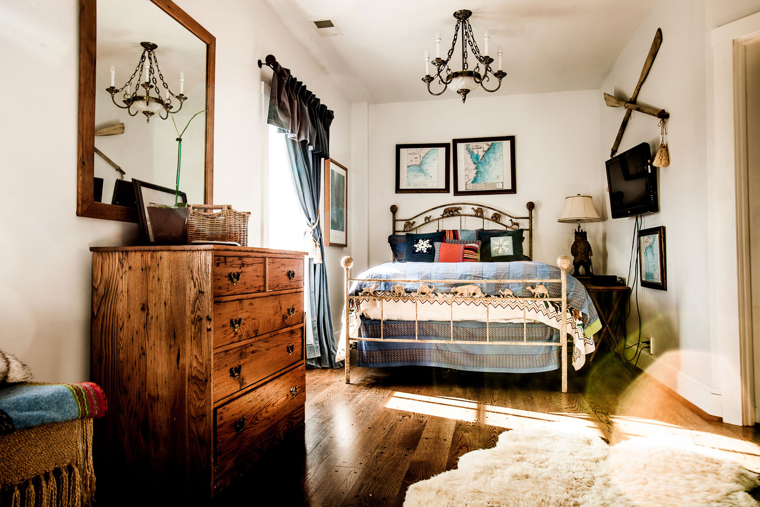  A smaller suite with a full sized bed, colorful maps hanging on the wall, and natural light spilling over the blue color themed room. 