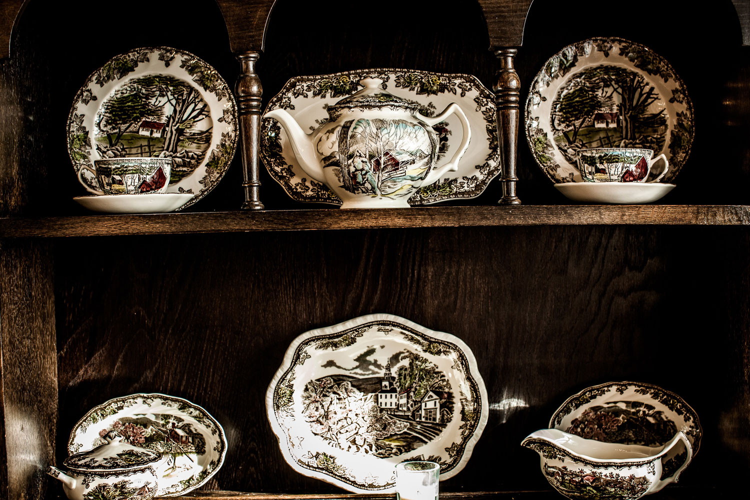  China tableware displayed in an antique wooden China cabinet. 