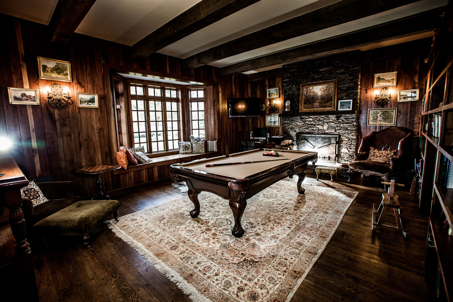  A typical English study room with a large bookcase on one wall facing an antique pool table. 