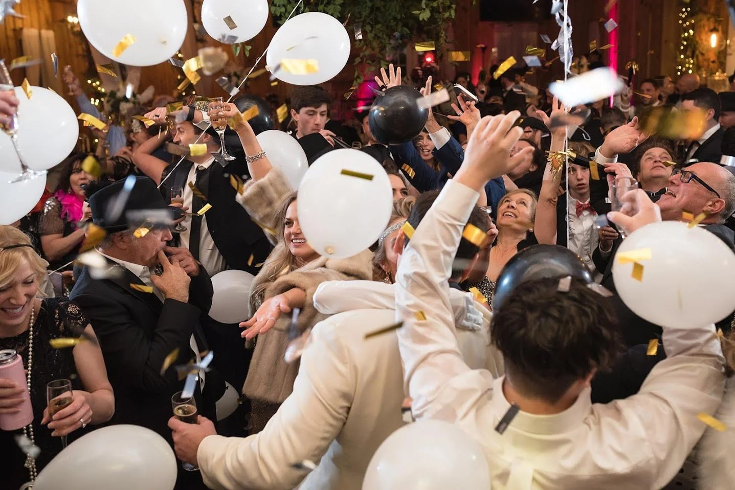 Wedding balloon drop with confetti falling over a packed dance floor.