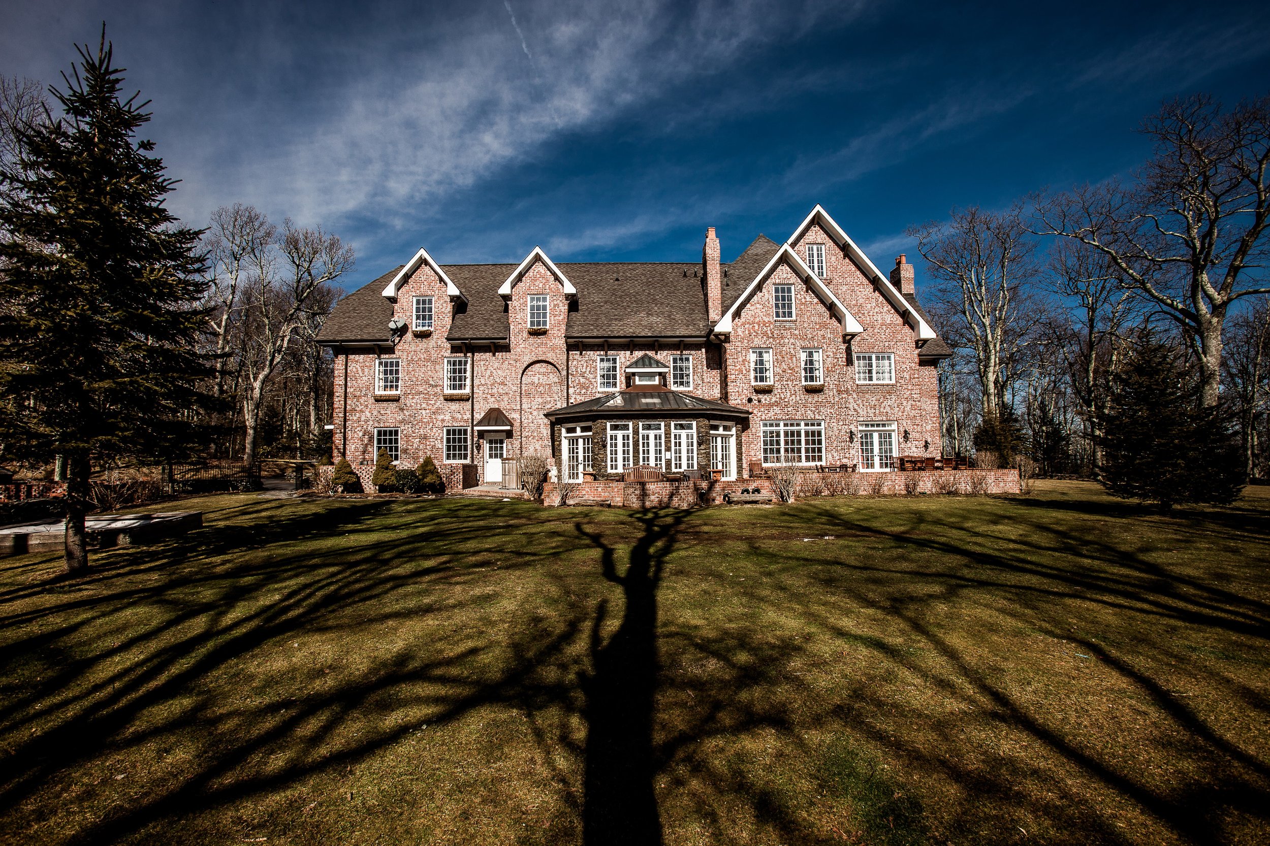  A large, manicured lawn featuring the back of Twickenham House. There is a large patio, a sun room, hot tub, and two wedding ceremony locations. 