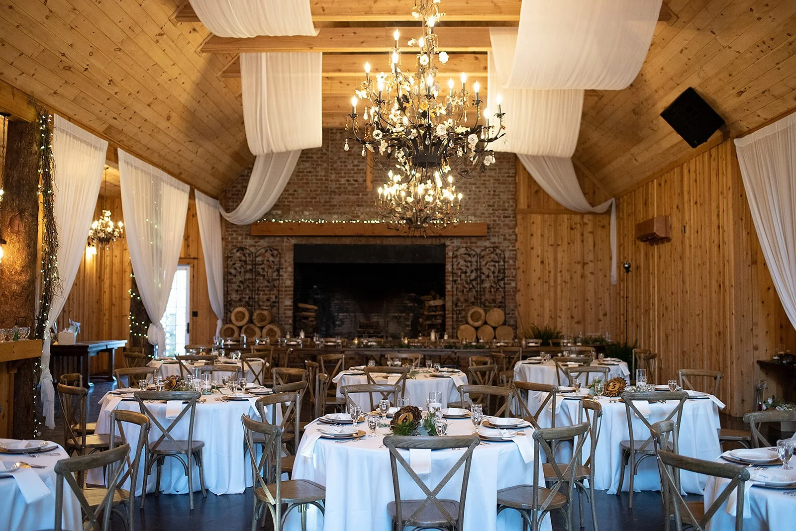 Round reception table with place settings, greenery, and glass cylinder candles as centerpieces.