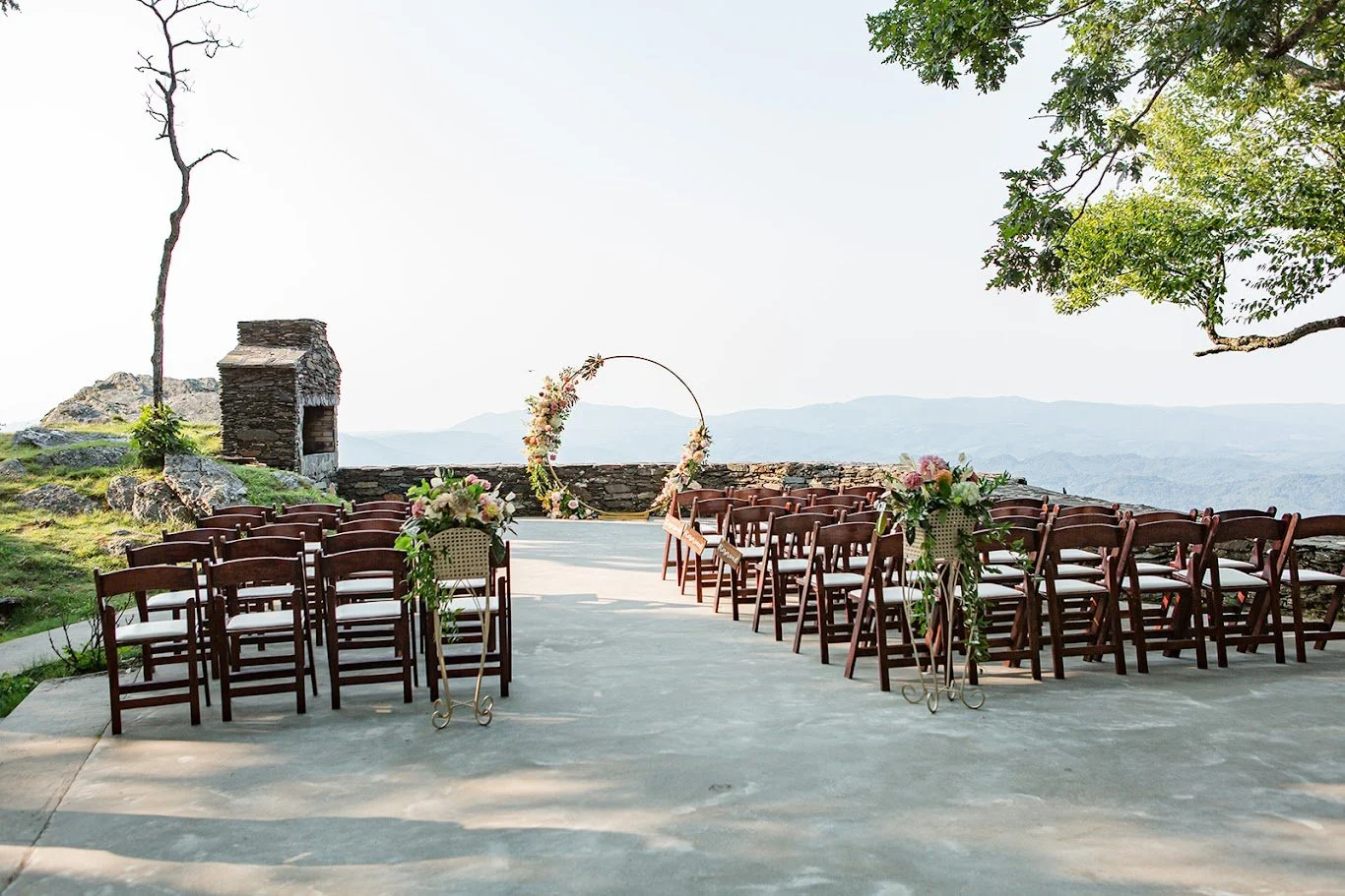 Mountaintop ceremony setup with wooden chairs facing a circular arch and sweeping mountain views