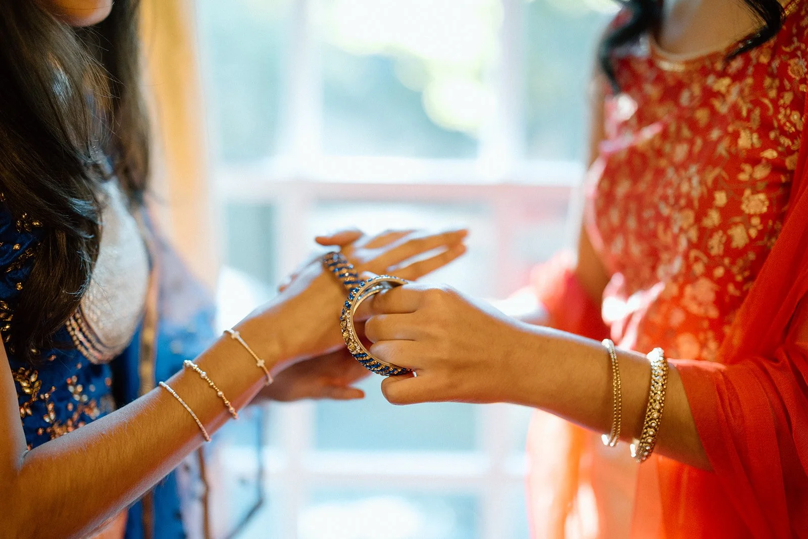 Close-up of an Indian couple holding hands, wearing floral garlands and traditional red and cream attire