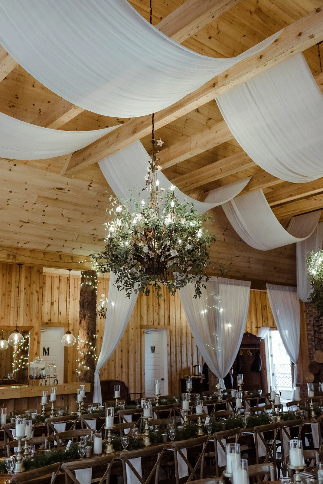 Wedding seating chart written on a vintage mirror hanging on a wood wall inside a rustic venue.