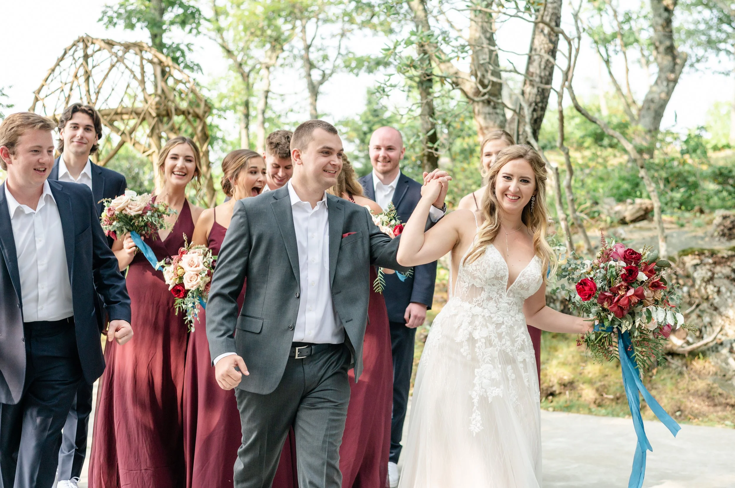 Bride dancing with friends at a rustic indoor wedding reception while guests hold drinks and celebrate around her