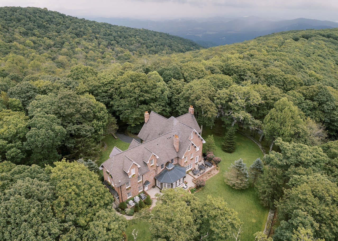 Aerial view of Twickenham House & Hall with surrounding lawns and forested mountains