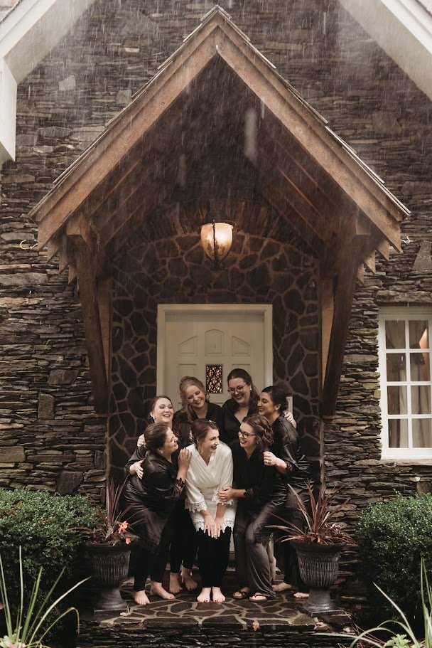 Bride and wedding party gathered for a portrait inside the doorway of a brick estate wedding venue.