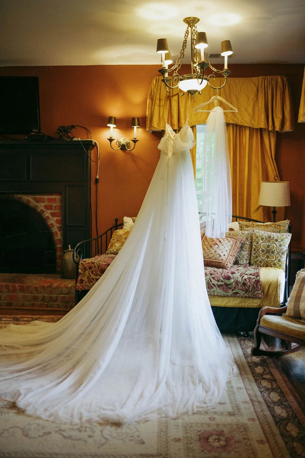 Wedding dress hanging in a bridal suite with a long train draped across the room.