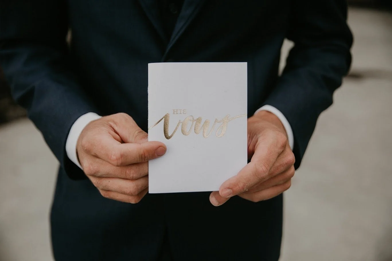Groom holding a wedding vow booklet for a close-up detail photo before the ceremony.