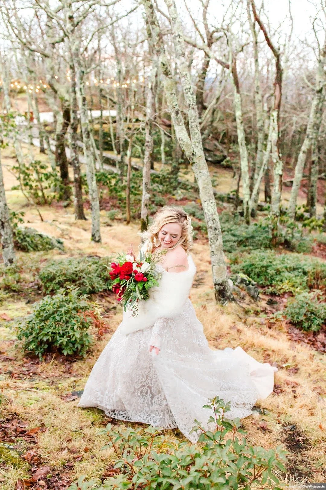 Bride and groom holding hands on a rocky cliff with a mountain view in the background.