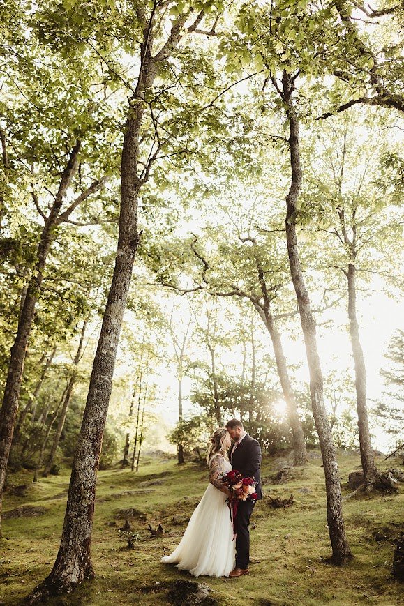 Couple exchanging vows at an overlook ceremony with floral arrangements and mountain views