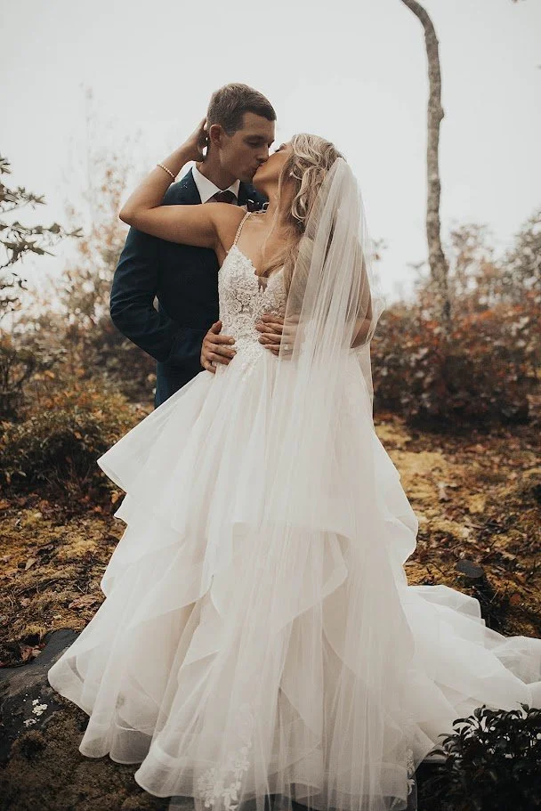 Closeup of the bride and groom kissing, showing the bride’s veil and lace bodice.