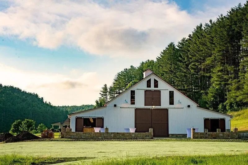 White barn wedding venue exterior with large doors and mountain views in the background