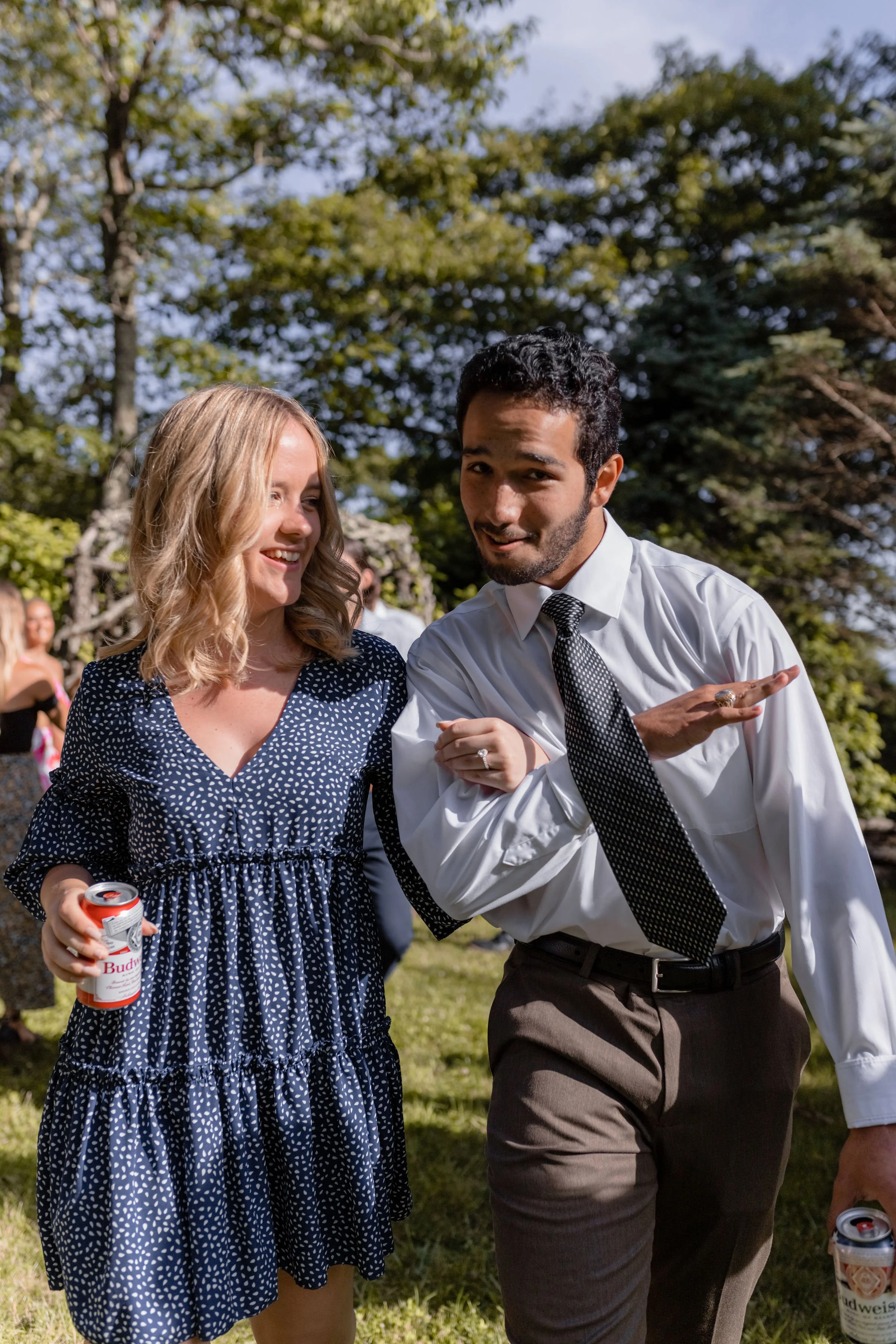 Couple laughing together during an outdoor wedding weekend party in sunny garden surroundings.