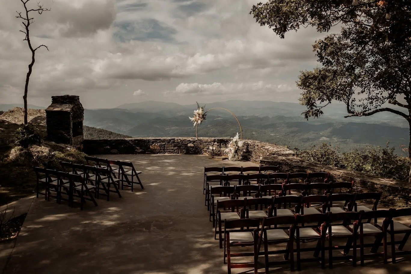 Mountaintop wedding ceremony site with rows of chairs on a stone terrace overlooking layered mountains