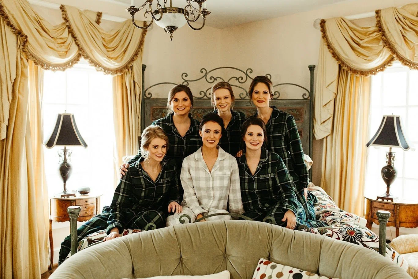 Bride and bridesmaids sitting on a bed in matching pajamas during getting ready.