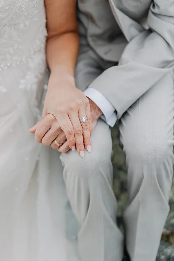 Close-up of the bride and groom holding hands showing their wedding rings