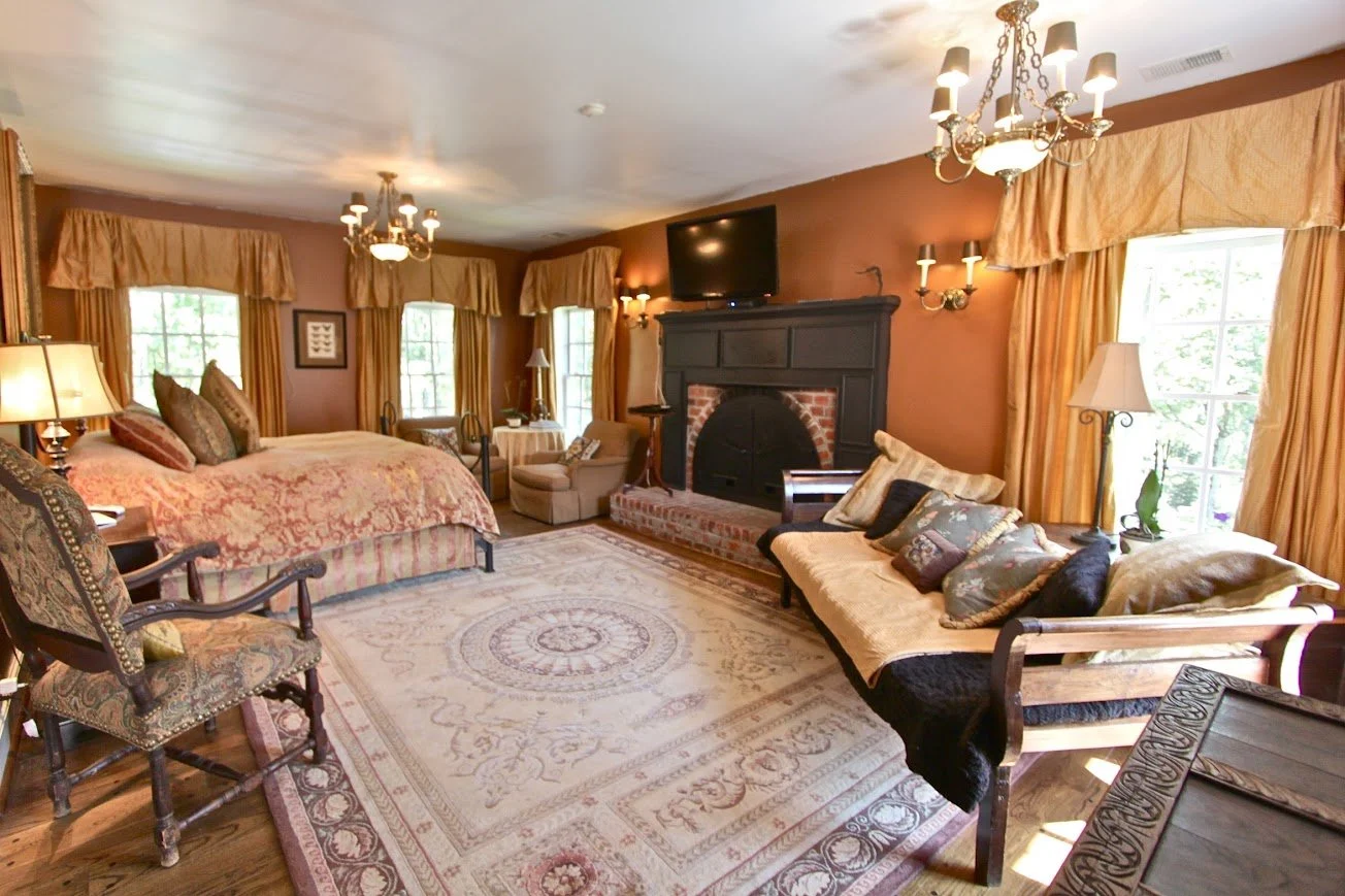 Bridal suite bedroom with a fireplace, seating area, and warm traditional decor.