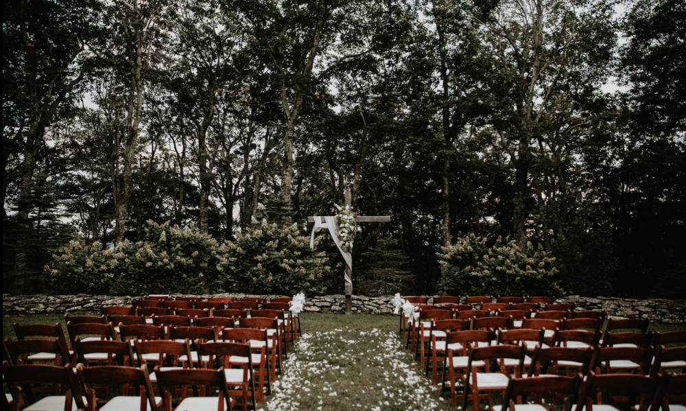 An exterior view of Twickenham House in the North Carolina mountains under a bright sky, surrounded by lush green trees.