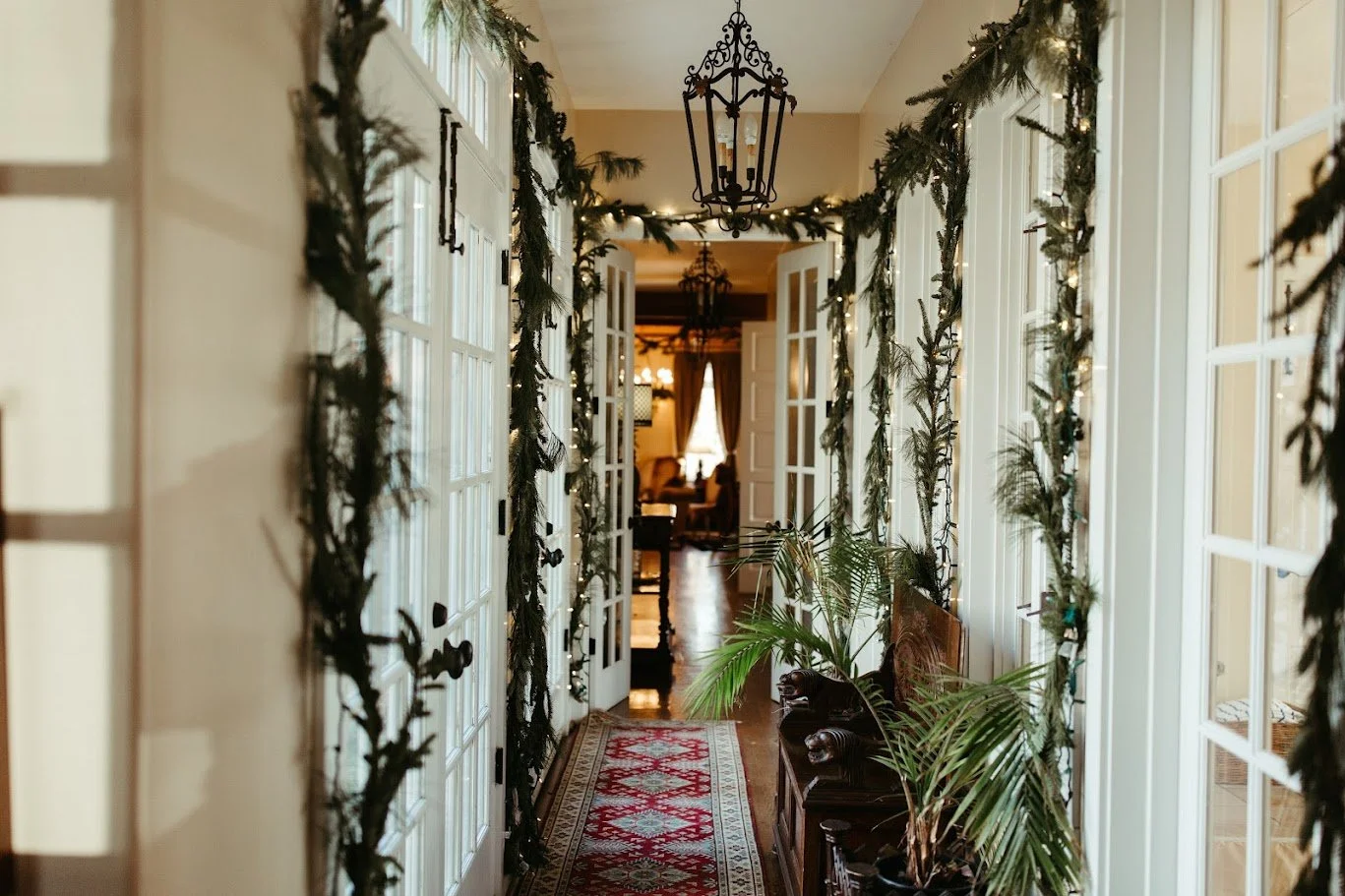 Wedding venue entryway decorated with hanging greenery, warm lights, and floral accents.