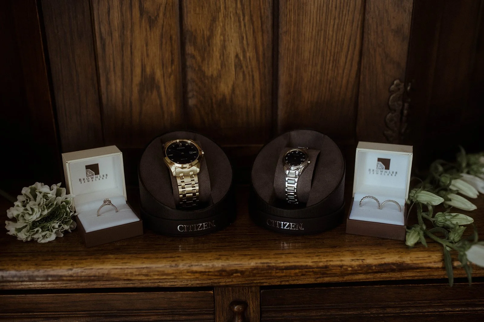 Wedding details with two watches and rings displayed on a wooden dresser