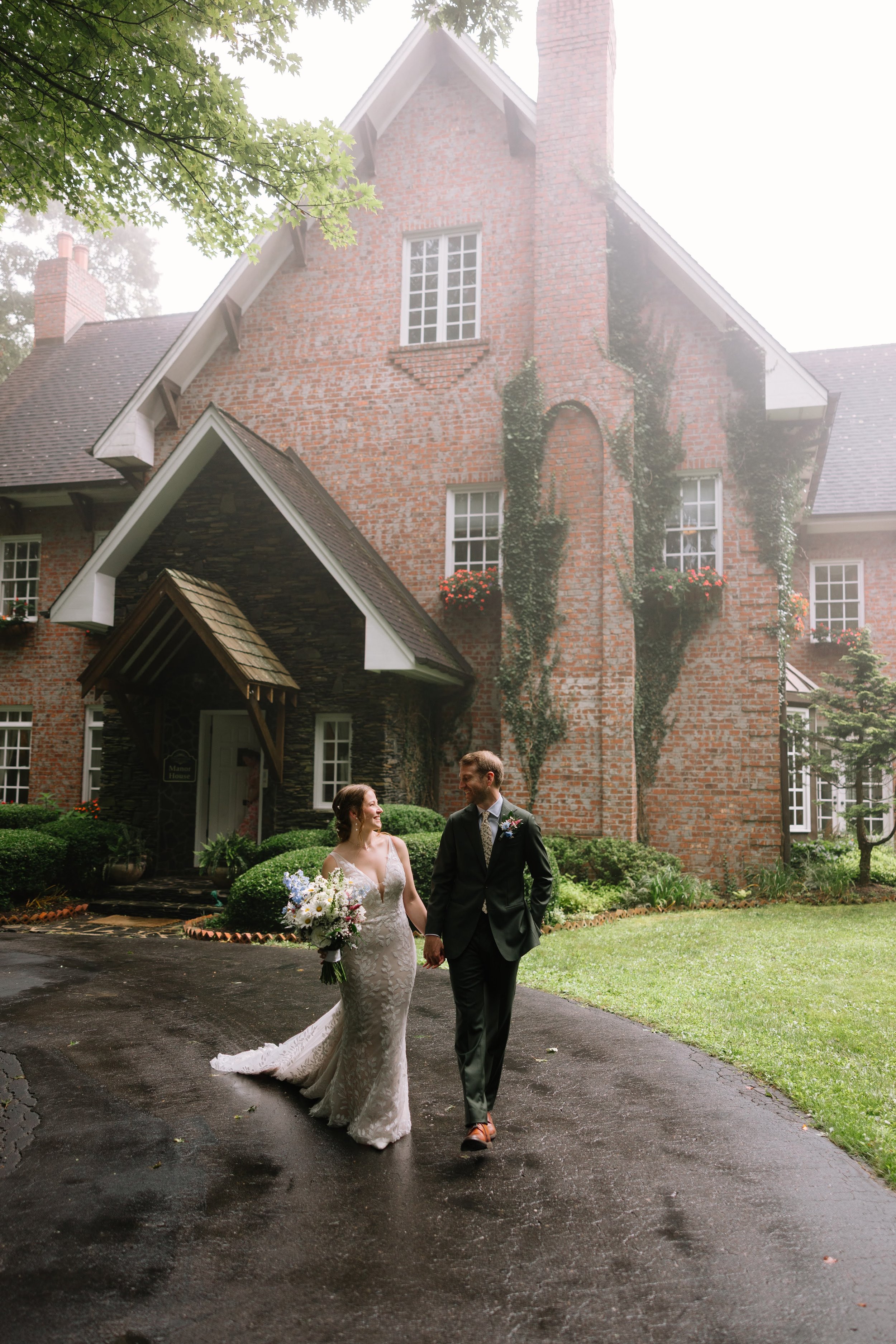 Bride and groom walking hand in hand in front of a brick estate wedding venue.