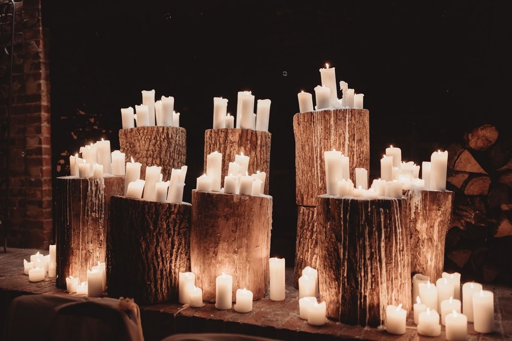 Romantic wedding candle display with pillar candles arranged on stacked wood logs