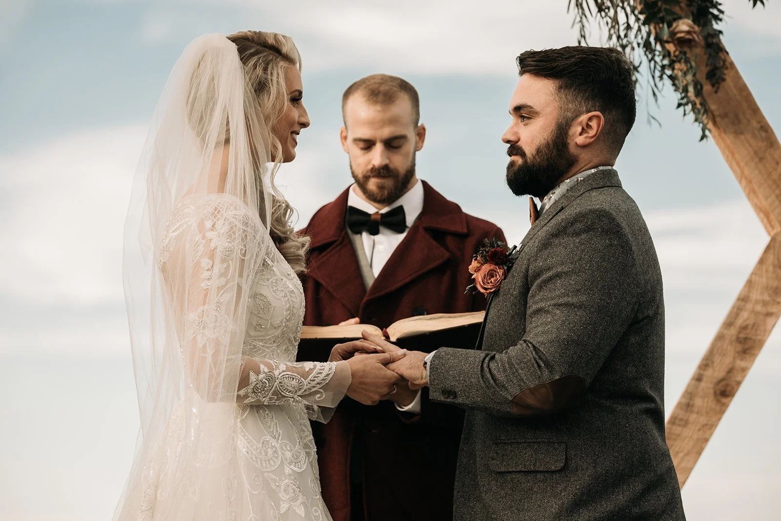 Bride and groom exchanging rings during an outdoor mountain wedding ceremony with an officiant nearby.