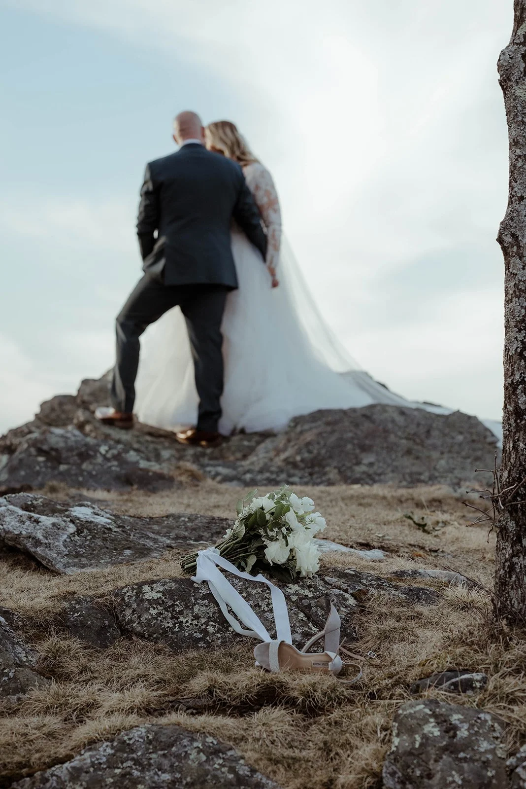 Bride looking over her shoulder in a lace sleeve wedding dress while holding a white bouquet.