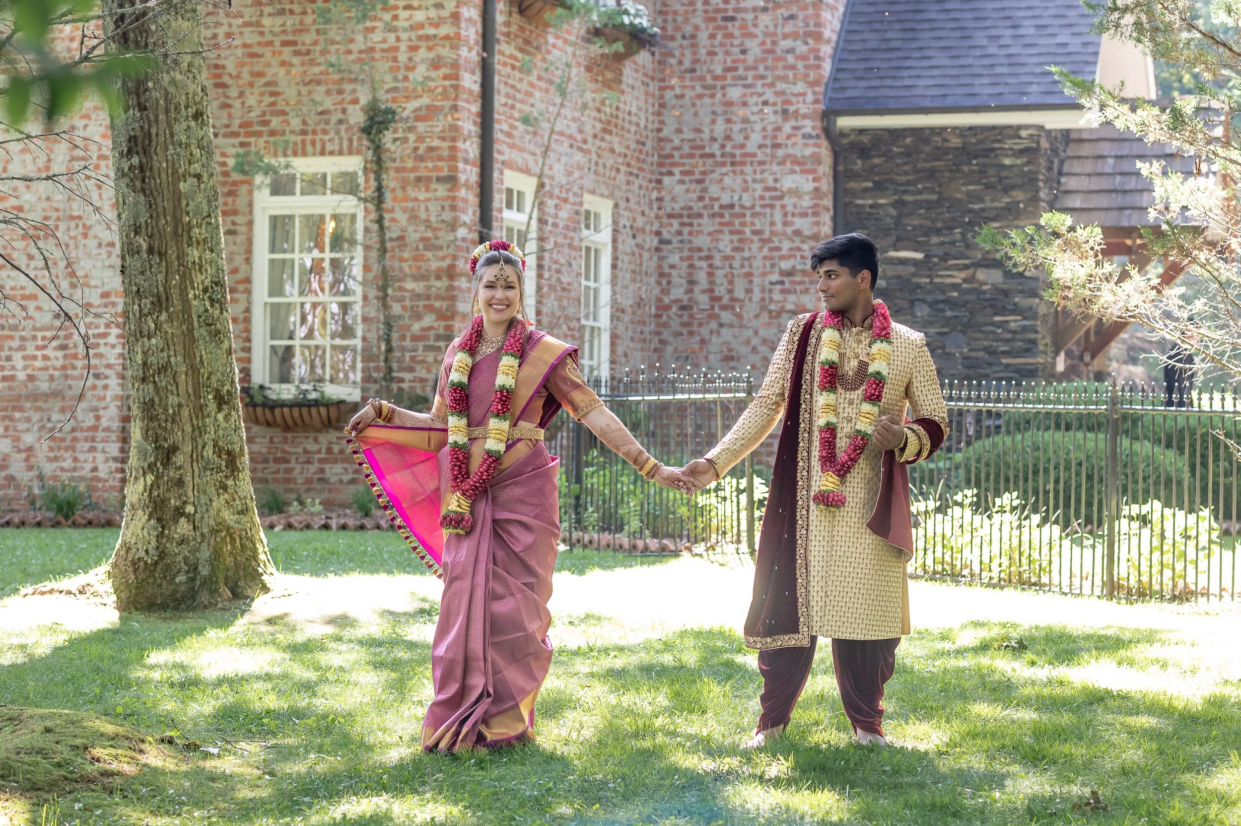 Bride and groom holding hands while walking outside a historic brick estate wedding venue.