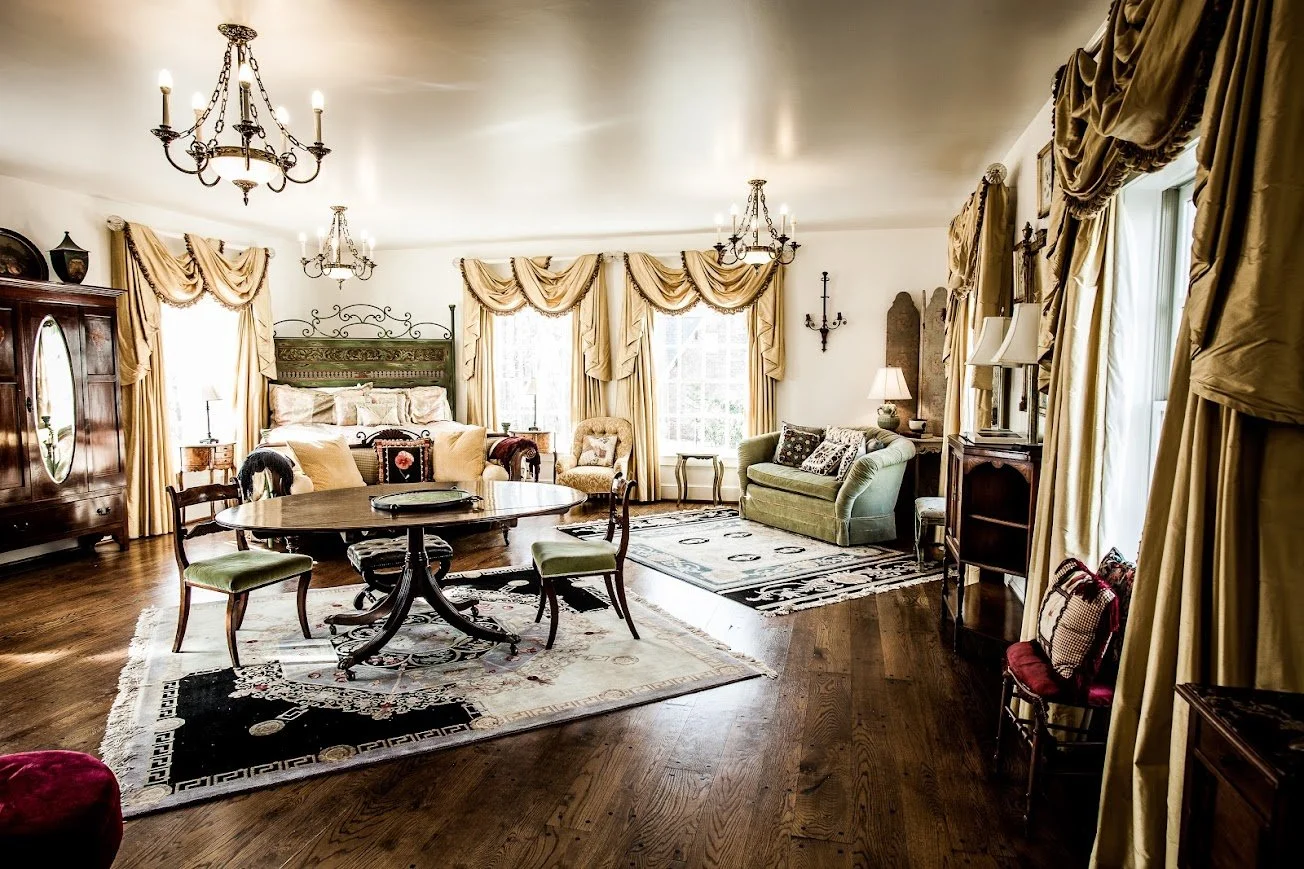 Wide view of a luxury bridal suite with vintage decor, chandeliers, and sitting area.