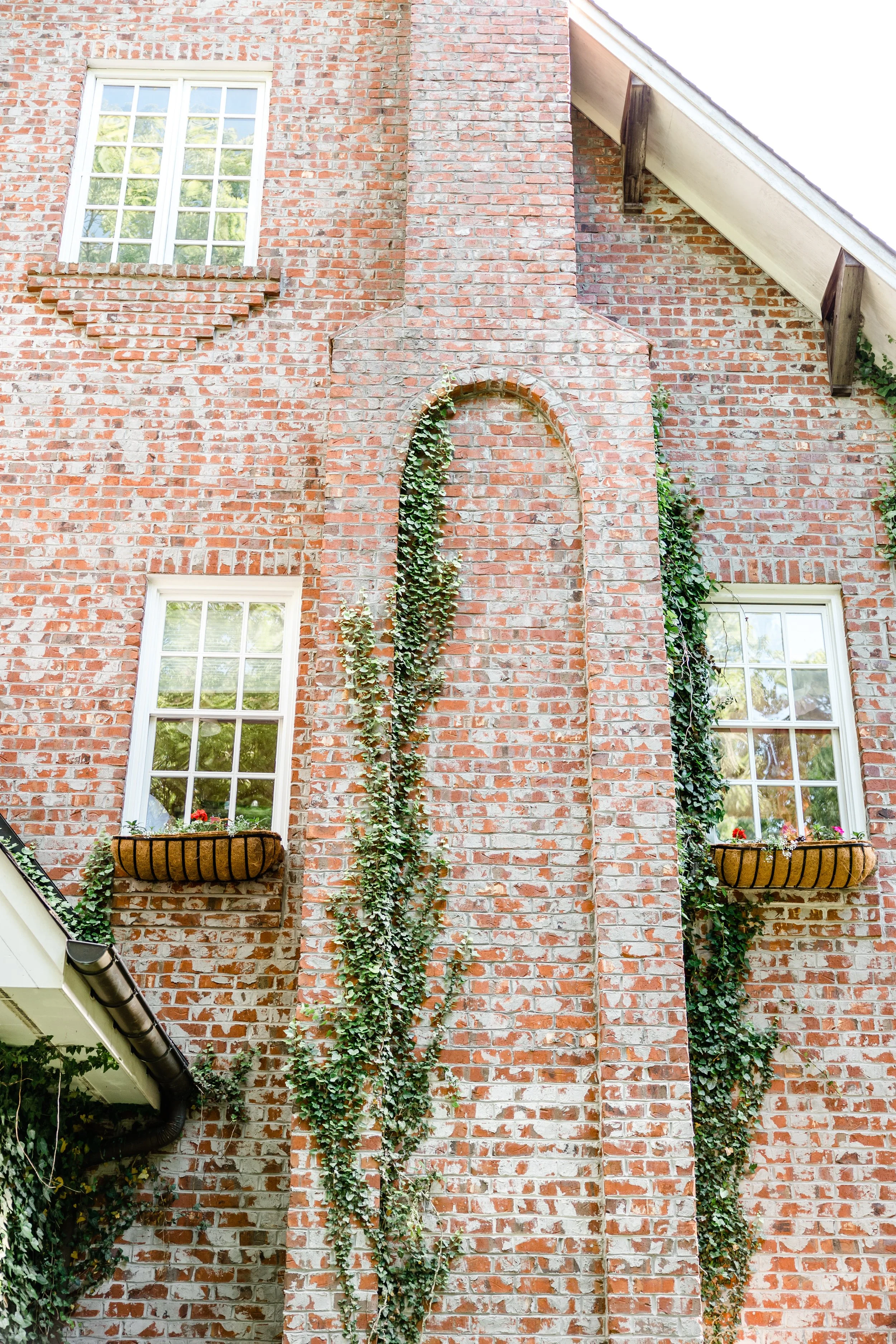 Ivy-covered brick estate wedding venue exterior with tall windows and flower boxes.