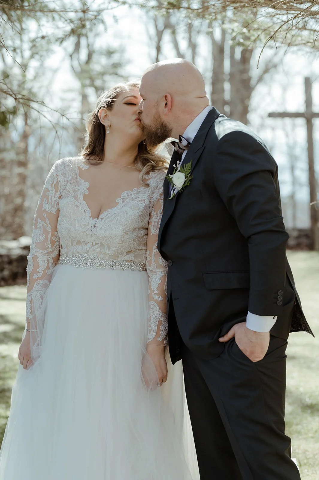 Rustic barn wedding reception with wood beams, white draping, and a hanging greenery chandelier.