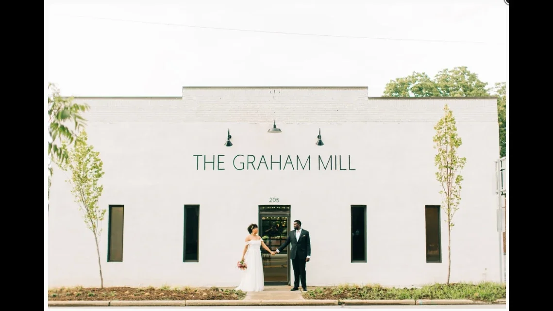 Couple holding hands in front of The Graham Mill wedding venue building