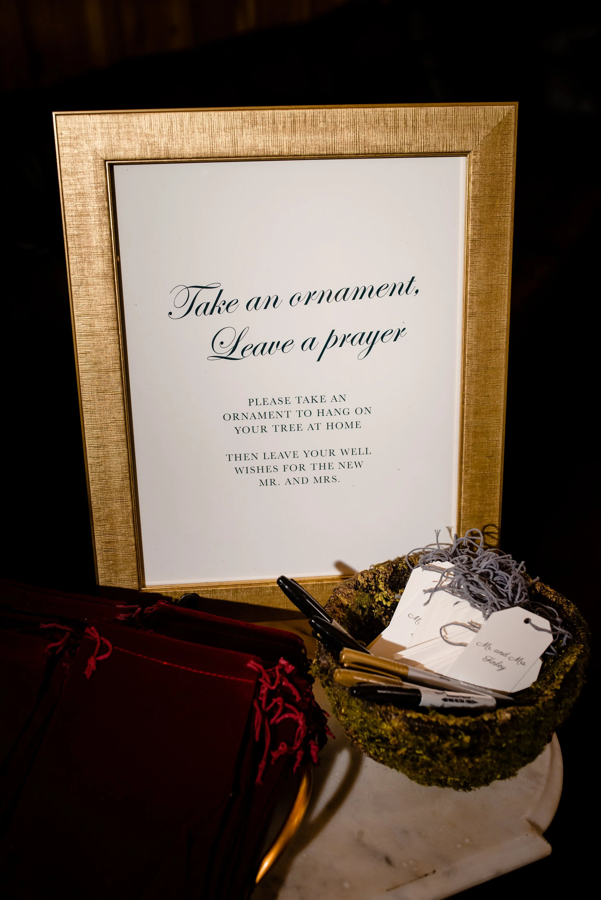 Wedding sign that reads “Take an ornament, leave a prayer” displayed with pens and tags.