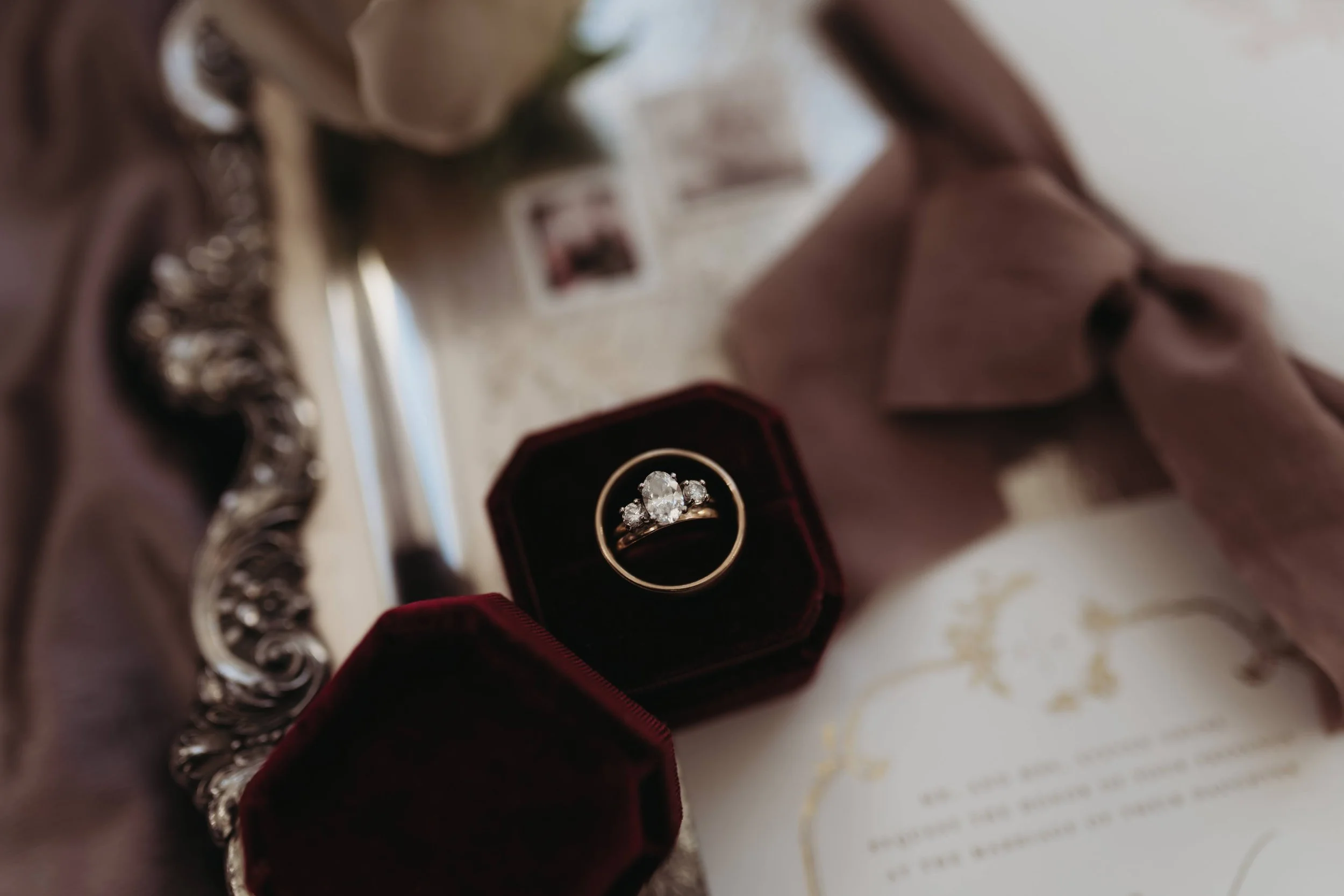 Wedding rings in a velvet ring box styled with invitation suite and ribbon details.