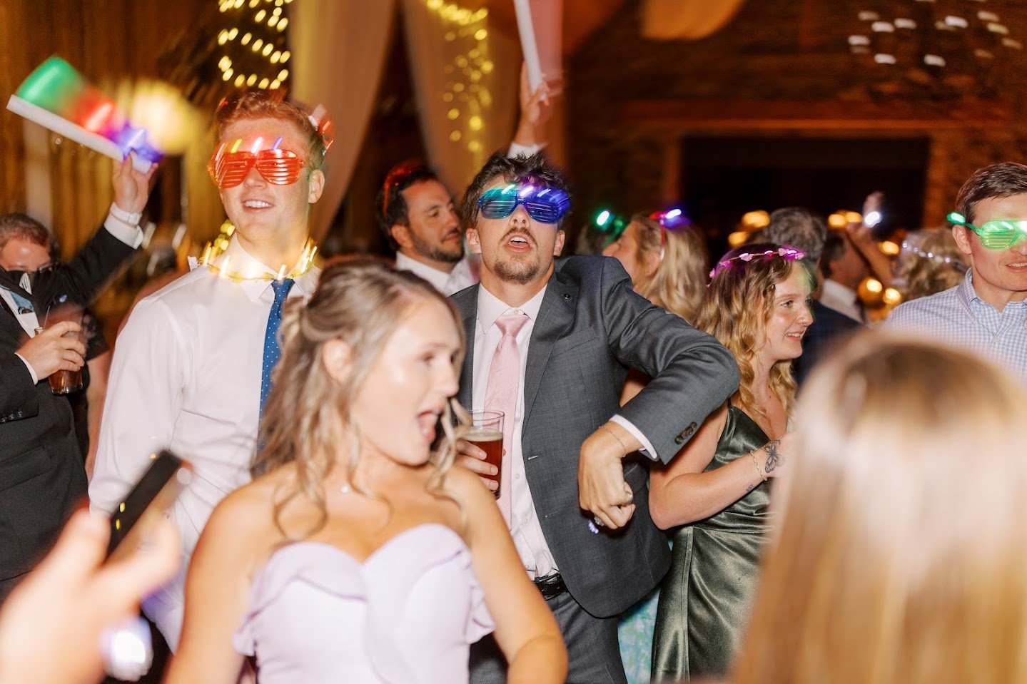 Wedding party dancing at the reception wearing funny light-up glasses.
