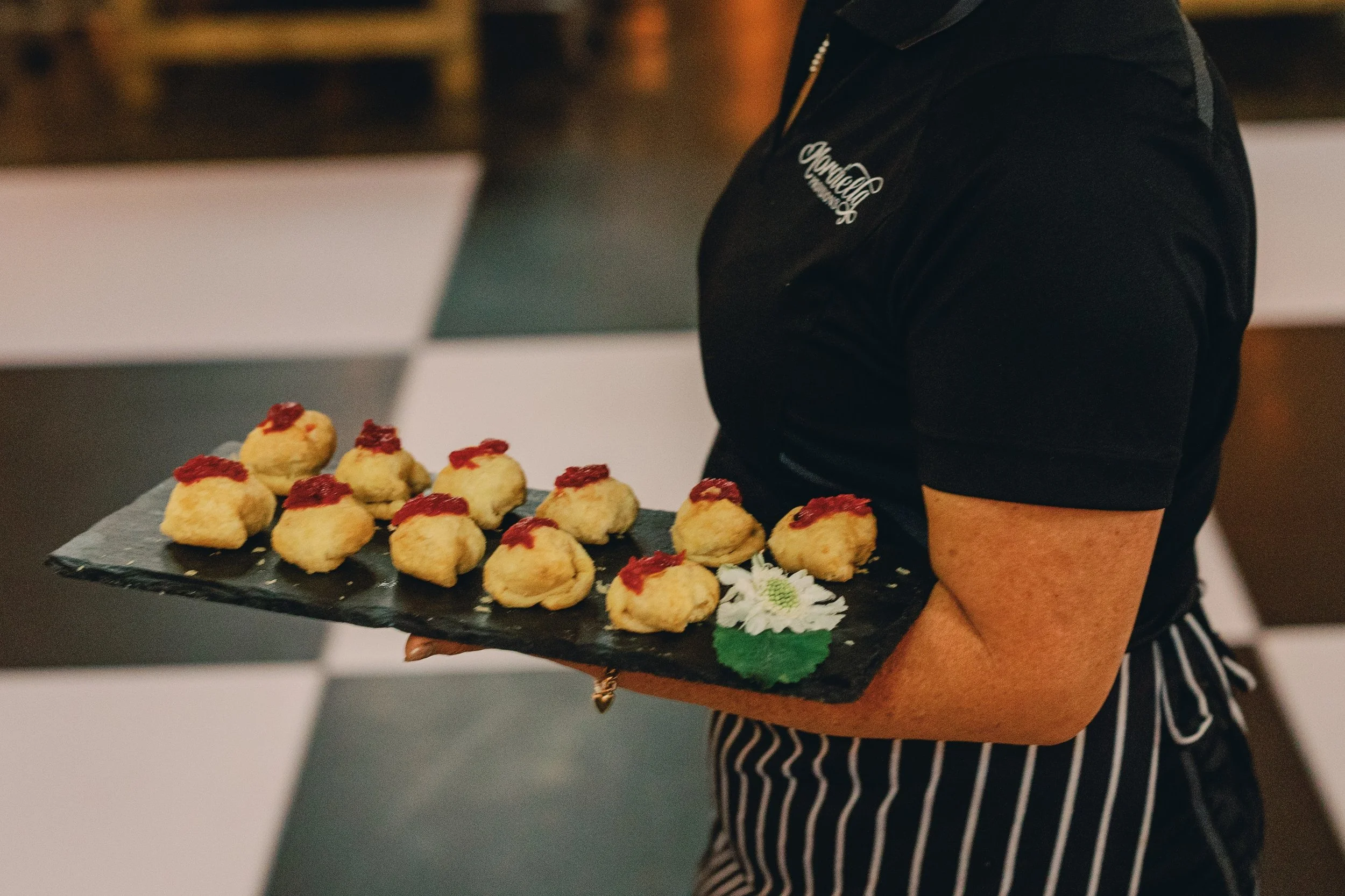 Server carrying a tray of passed appetizers during cocktail hour at a wedding reception