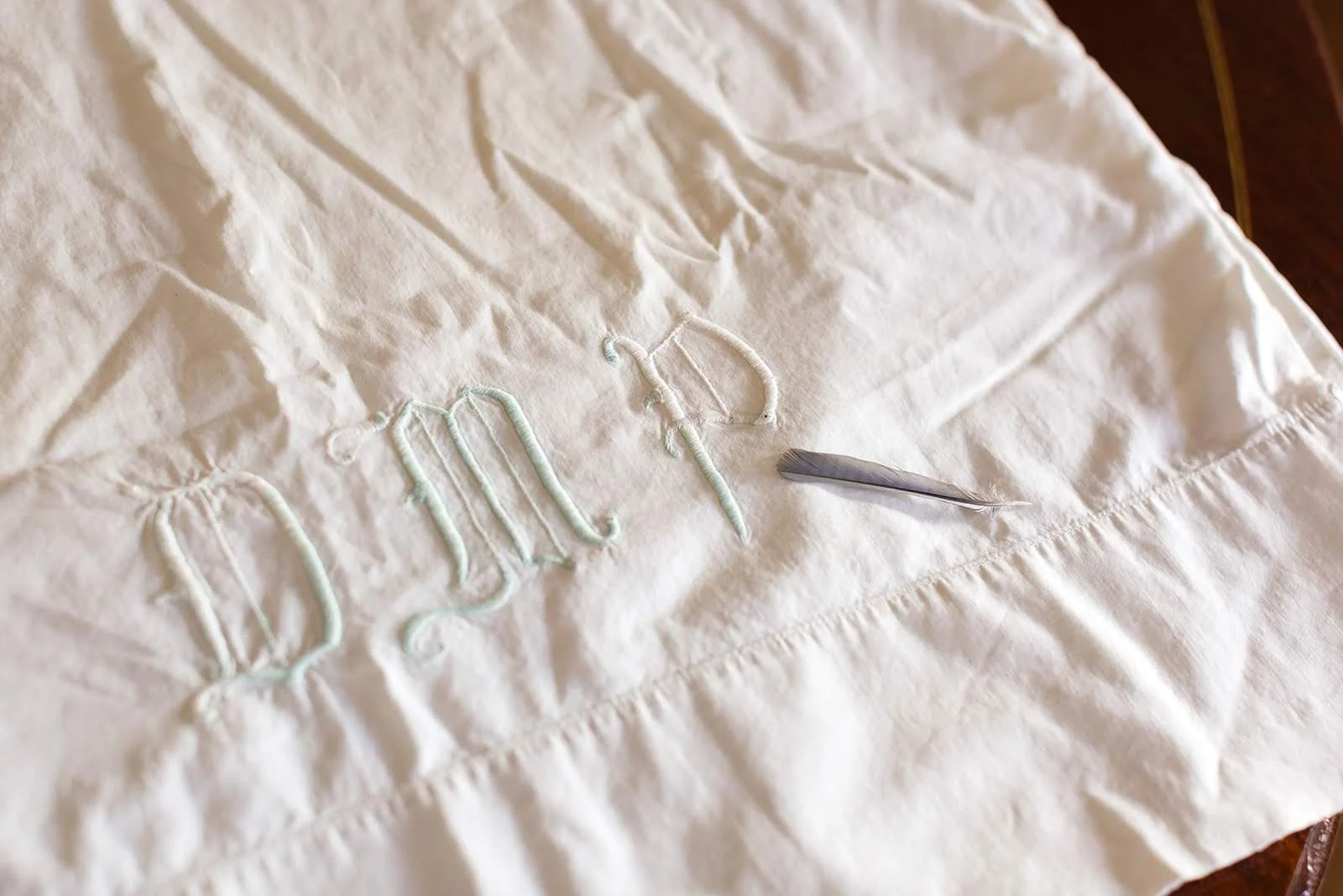 Monogrammed wedding dress hanger on a bed during the bride’s getting ready.