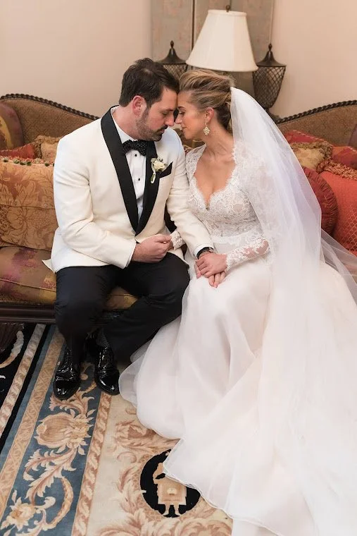 White floral centerpiece with feathers on a gold candelabra at a wedding reception