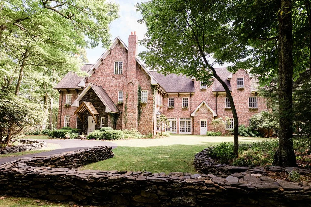 Wide view of the Twickenham House & Hall brick estate surrounded by trees and stone walls