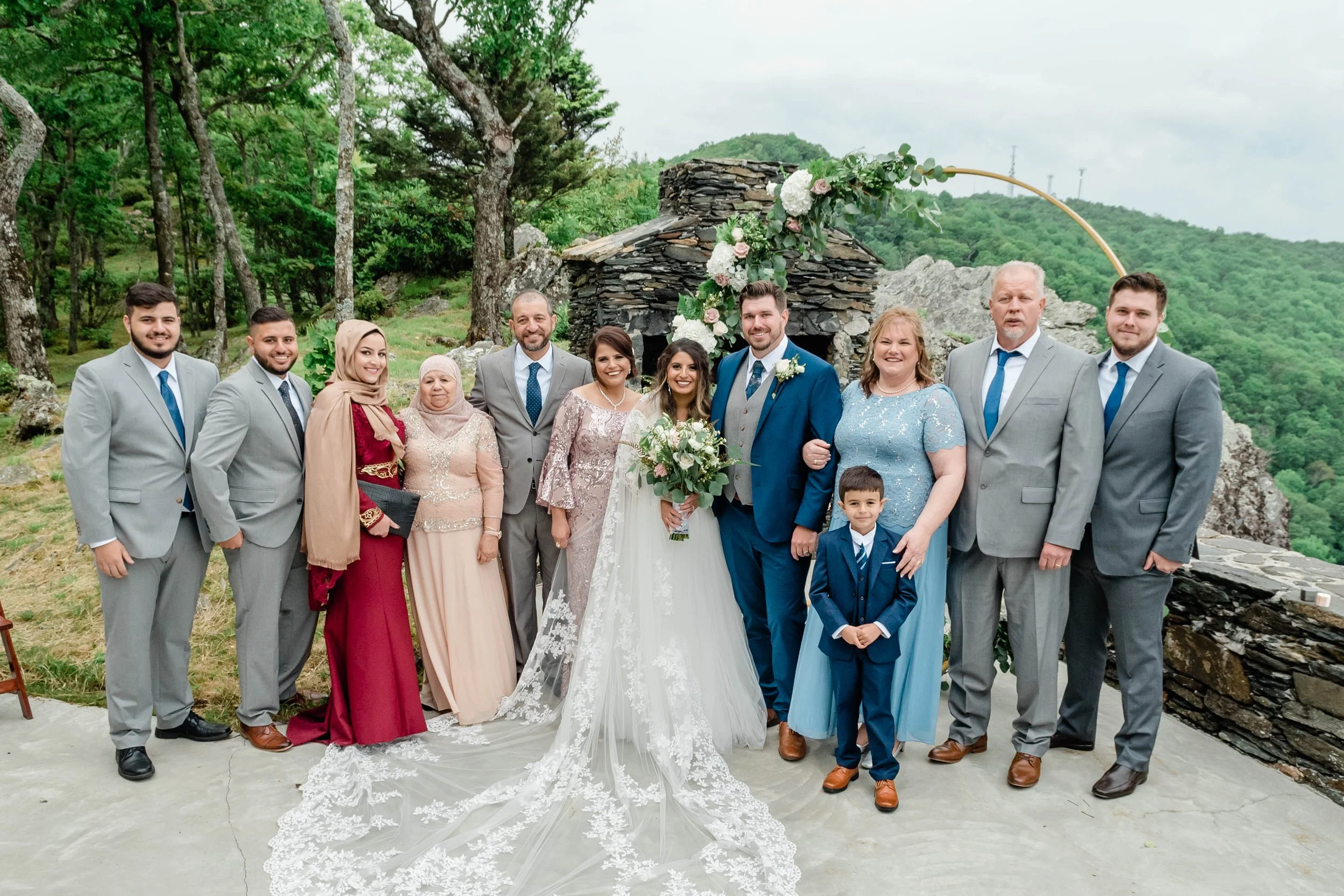 Bride and groom posing with family at a mountain overlook wedding ceremony location.