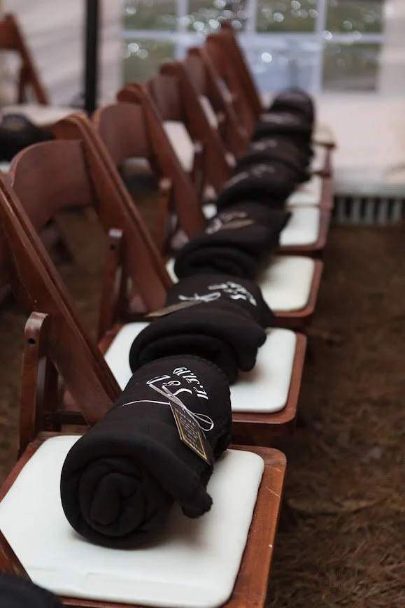 Rolled blankets placed on chairs for guests at an outdoor wedding ceremony