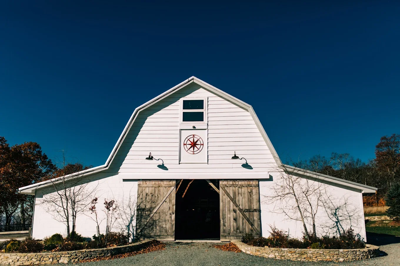 White barn wedding venue exterior with open wooden doors under a deep blue sky